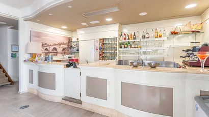 Banco bar bianco con scaffali di bottiglie alcoliche e decorazioni luminose