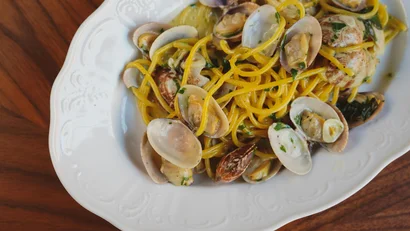 Spaghetti alle vongole in un piatto bianco su un tavolo di legno