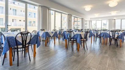 Sala da pranzo luminosa con tavoli apparecchiati e sedie nere