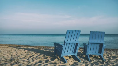 Due sedie blu sulla spiaggia di sabbia con vista sul mare calmo sotto cielo azzurro