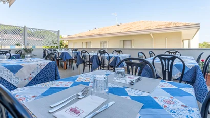 Tavoli apparecchiati con tovaglie blu all'aperto su terrazza di ristorante