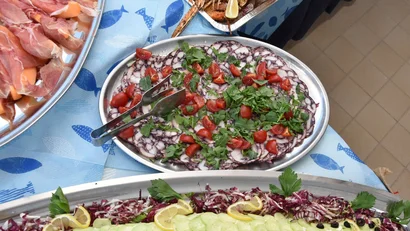 Vassoi di antipasti con salumi, verdure e frutti di mare su tovaglia blu con pesci