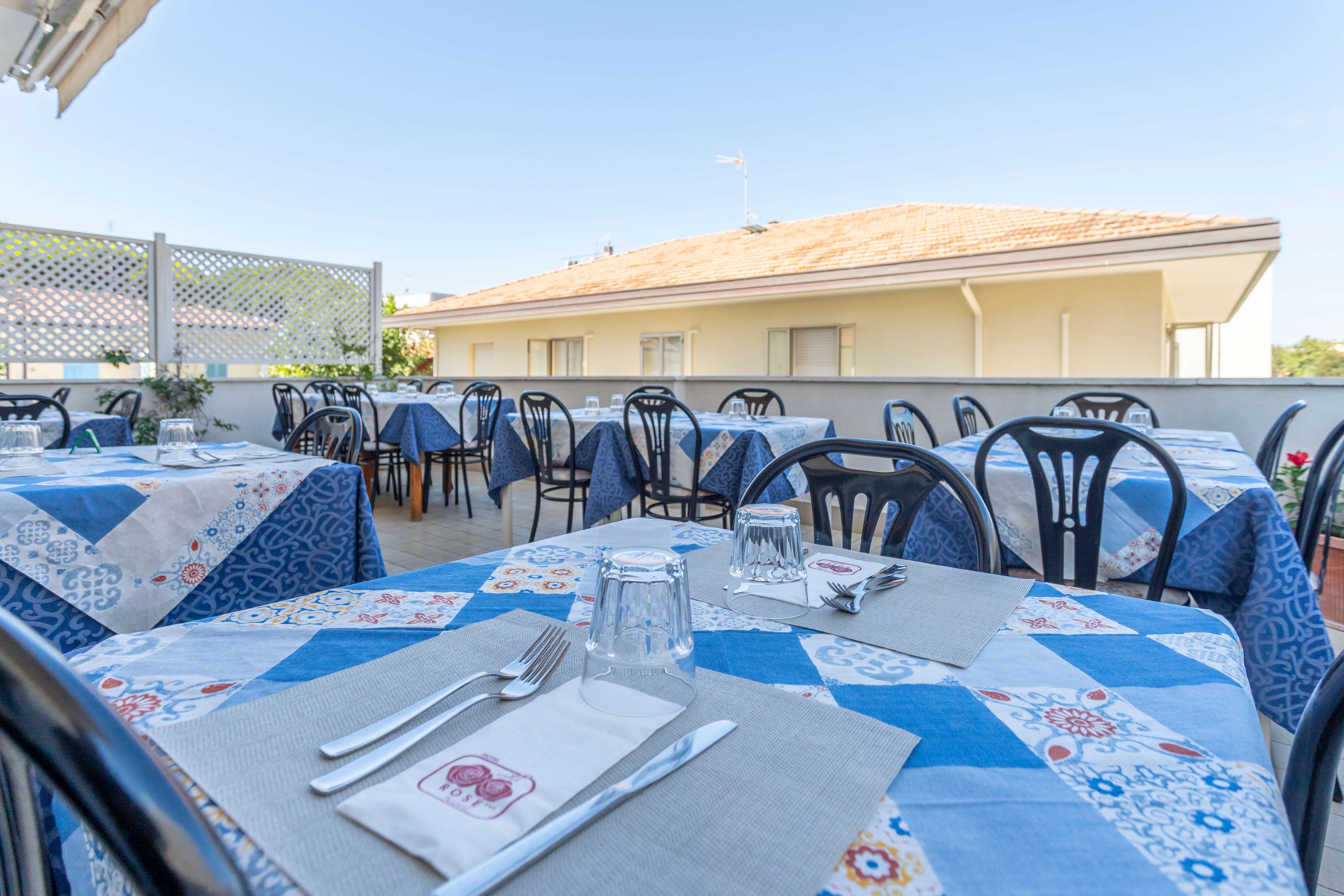 Tavoli apparecchiati con tovaglie blu all'aperto su terrazza di ristorante